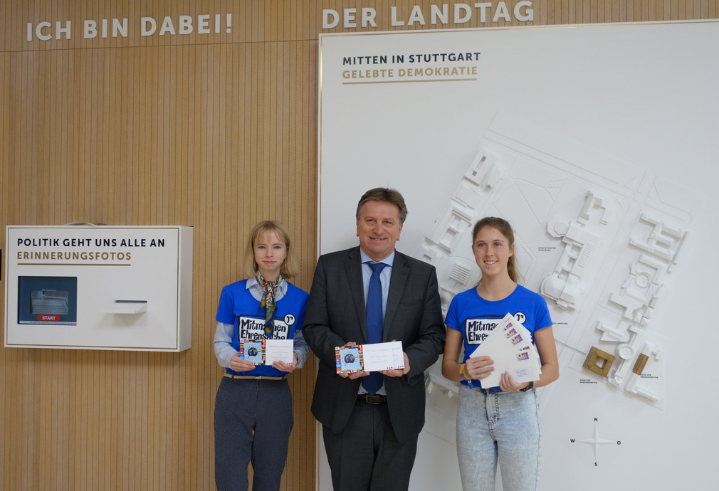 Gruppenfoto von zwei Schülerinnen mit Minister Manne Lucha im Medienzentrum des Landtags von Baden-Württemberg