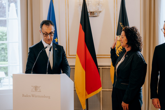 Petra Krebs steht mit erhobener Hand vor Ministerpräsident Cem Özdemir.