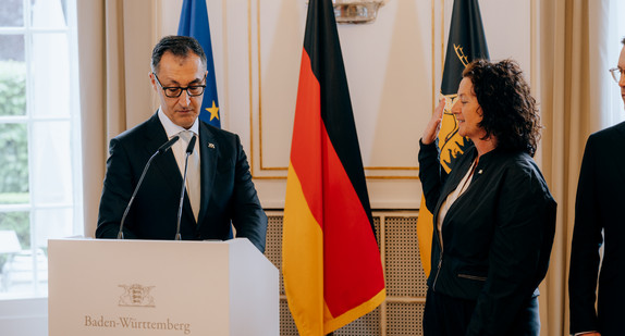 Petra Krebs steht mit erhobener Hand vor Ministerpräsident Cem Özdemir.