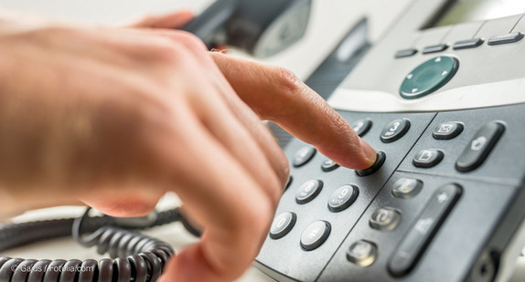 Hand tippt auf Nummernfeld eines Telefons