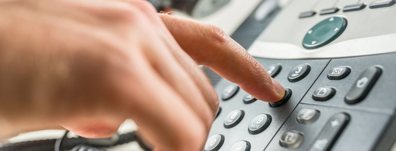 Hand tippt auf Nummernfeld eines Telefons