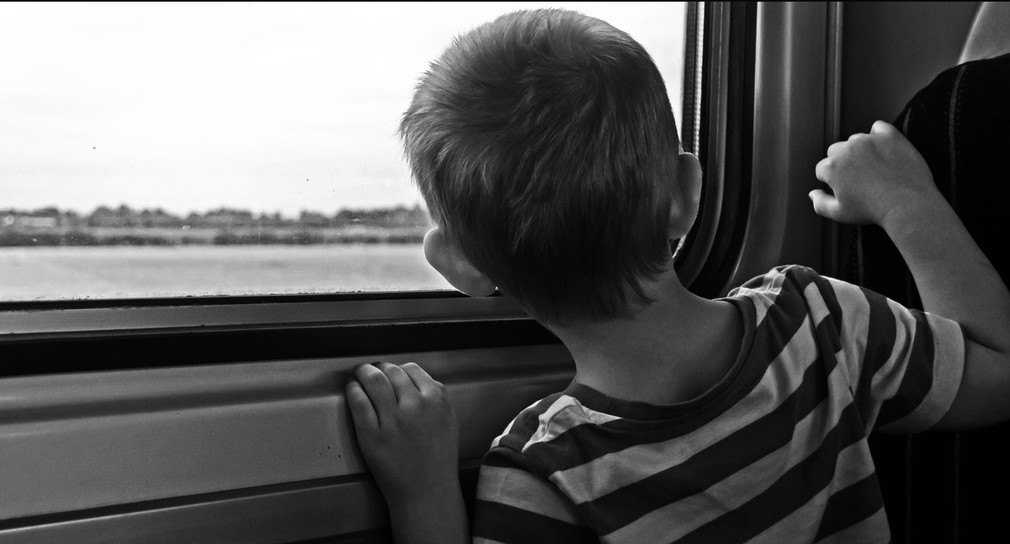 Kleiner Junge schaut aus Fenster eines Zuges