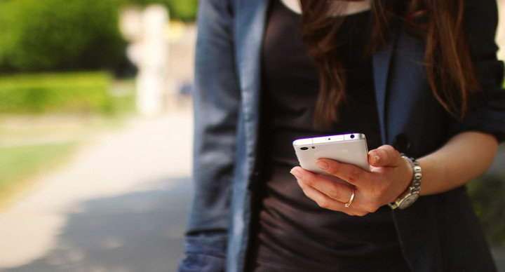 Junge Frau hält Handy in der Hand.