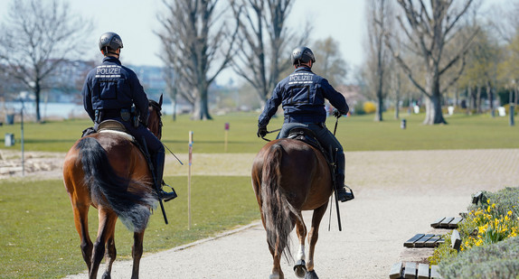Berittene Polizisten reiten auf Streife durch Park.