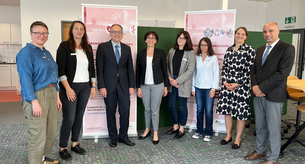 Gruppenfoto: Staatssekretärin Dr. Ute Leidig steht mit mehreren Mitgliedern des Interkulturellen ÄrztInnen-Netzwerks vor zwei Roll-ups des Netzwerks.