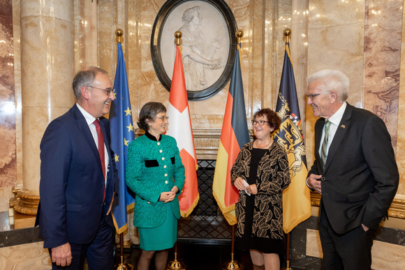 Künstliche Intelligenz Vertiefte Zusammenarbeit mit der Schweiz bei Künstlicher Intelligenz (von links nach rechts:) Guy Parmelin, Caroline Parmelin, Gerlinde Kretschmann und Winfried Kretschmann unterhalten sich heiter.