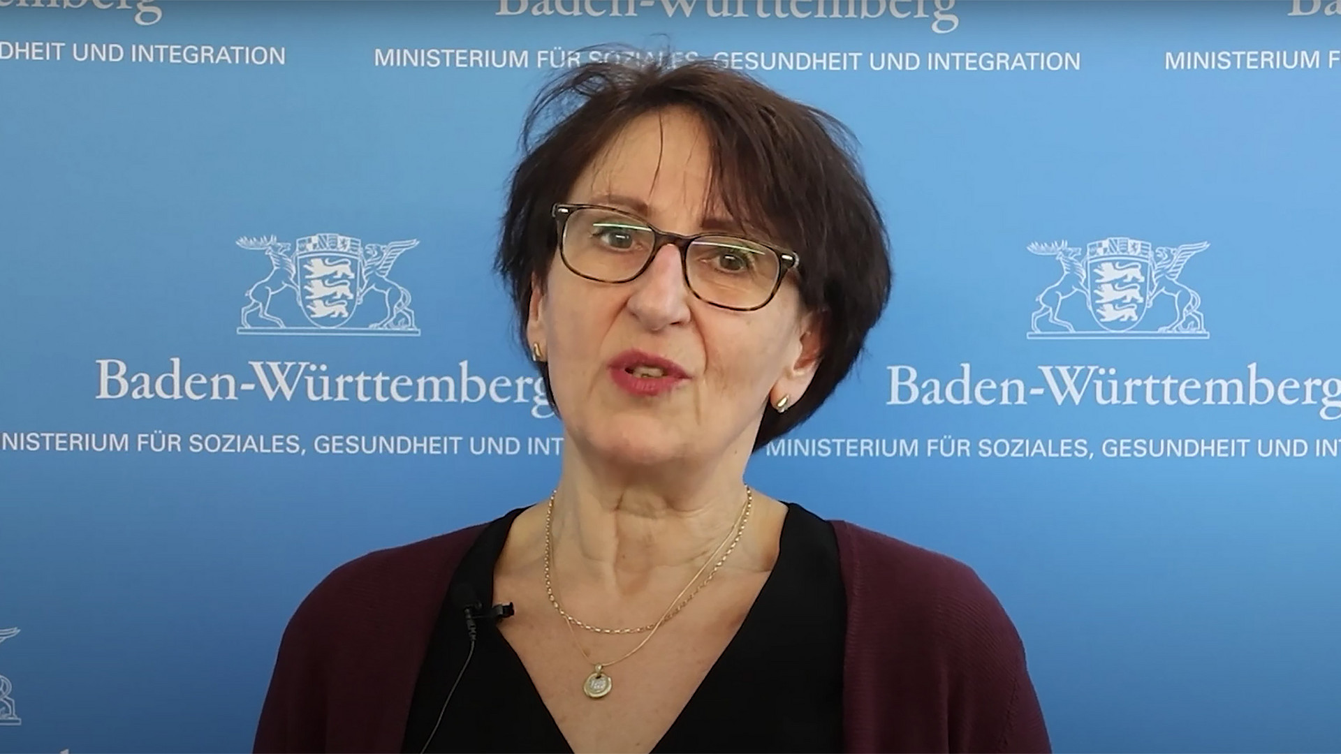 Staatssekretärin Dr. Ute Leidig vor Leinwand mit Logo des Sozialministeriums Baden-Württemberg