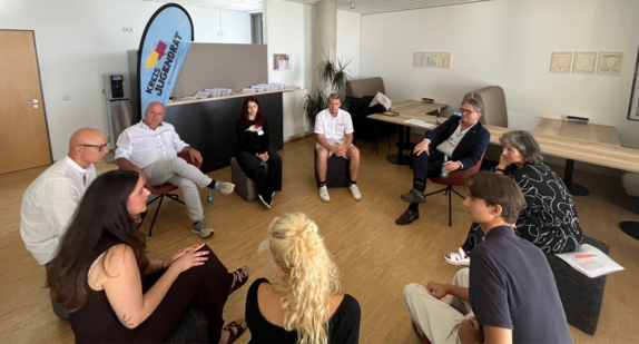 Minister Manne Lucha sitzt in Friedrichshafen mit dem Kreisjugendrat Bodenseekreis und dem Jugendkreisrat Konstanz zusammen. Alle sitzen sich im Kreis gegenüber und tauschen sich über die Anliegen der jungen Menschen aus.