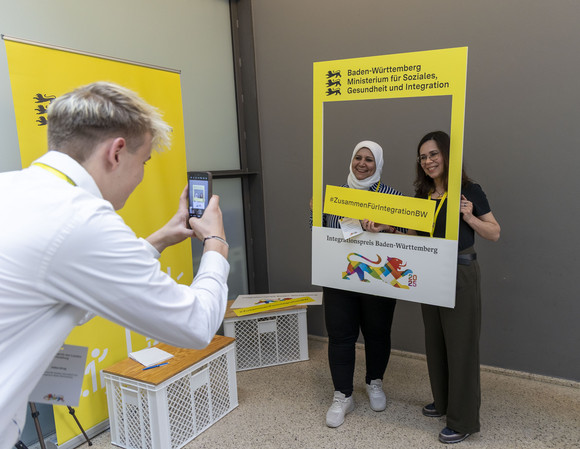 Preisverleihung Integrationspreis des Landes Baden-Württemberg Zwei Frauen mit Selfie-Fotorahmen mit dem Aufdruck "Integrationspreis Baden-Württemberg".
